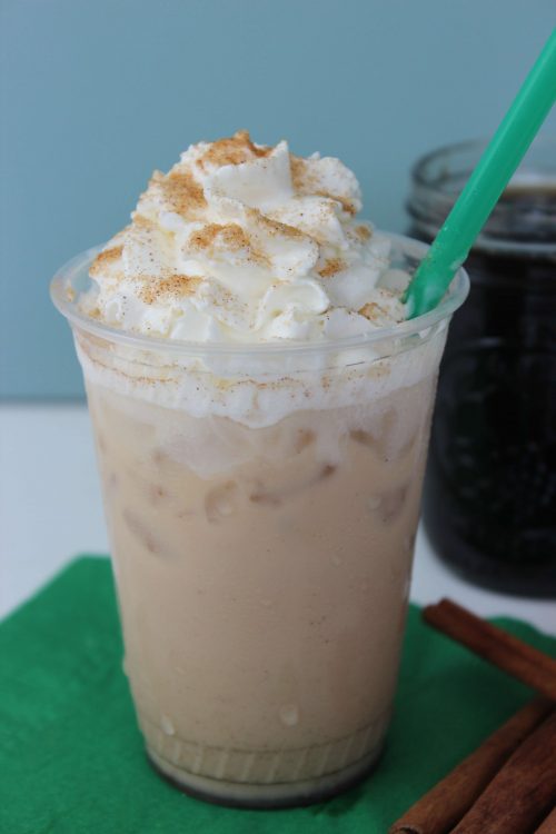 an ice cinnamon dolce latte topped with whipped cream, cinnamon, and a green straw. 