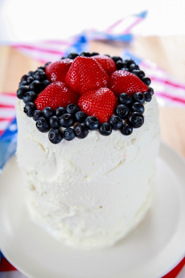 a watermelon fruit cake with whipped cream and topped with strawberries and blueberries. 