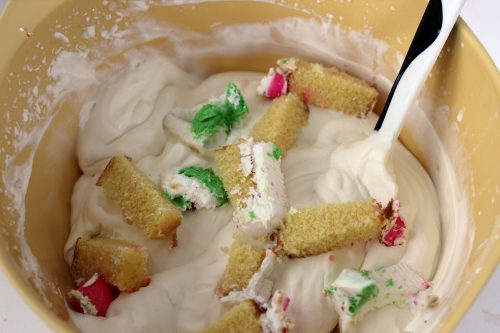an image showing birthday cake being mixed in a no churn vanilla ice cream base in a yellow bowl. 