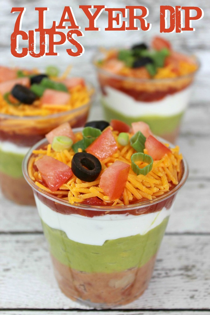 seven layer dip including beans, guacamole, salsa, and sour cream in individual plastic cups. 