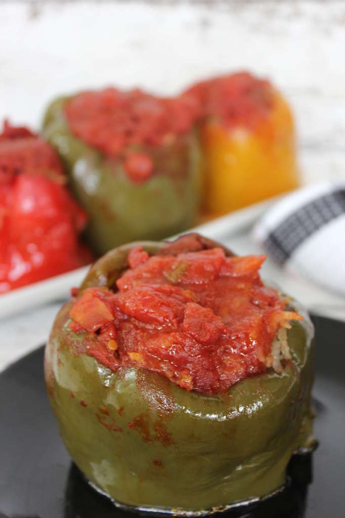 a stuffed green bell pepper made in the crockpot on a black plate.
