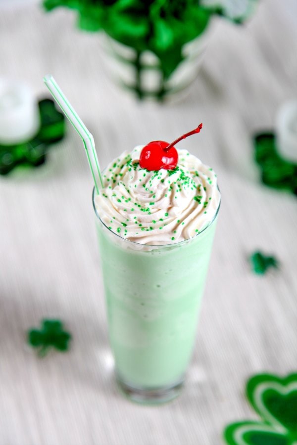 a homemade green shamrock shake topped with whipped cream, a cherry, and green sprinkles. 