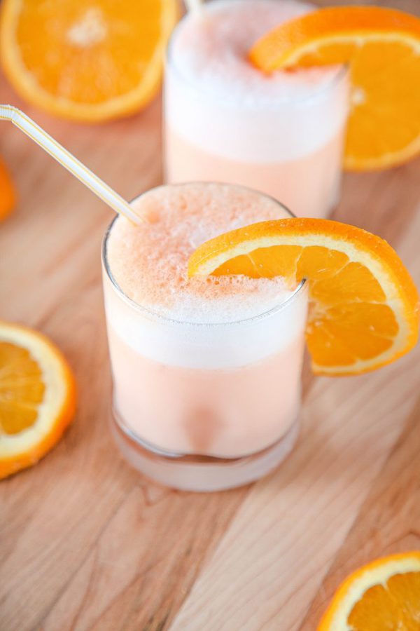 Two orange julius drinks garnished with an orange wedge.