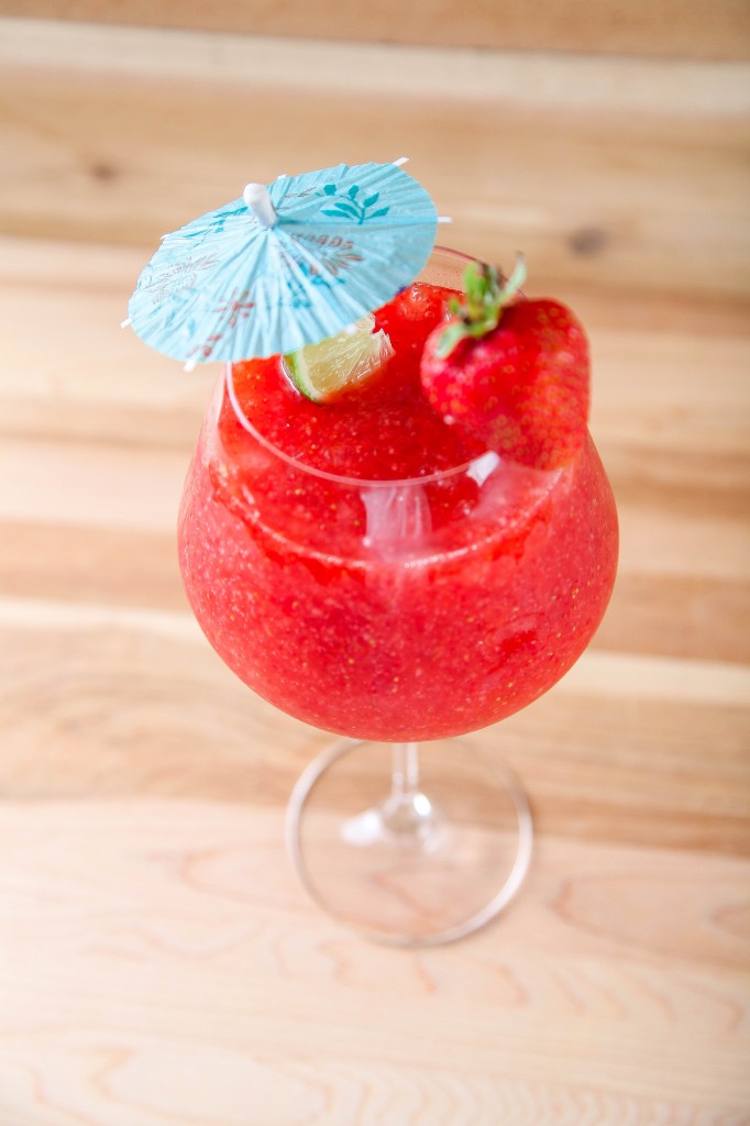 Strawberry Daiquiri garnished with a fresh strawberry, lime wedge and drink umbrella. 