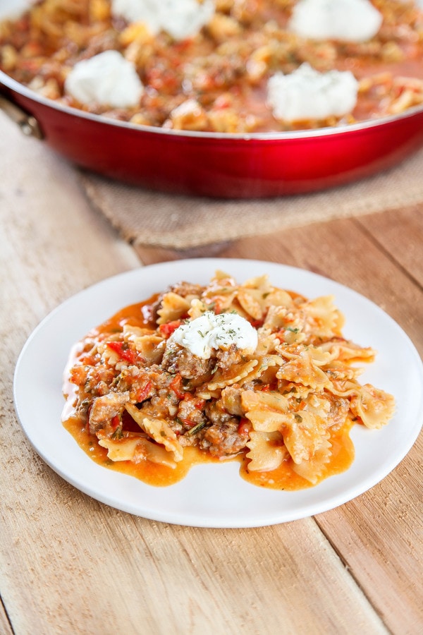 skillet lasagna with sausage, tomato sauce, farfalle pasta, and topped with ricotta cheese.