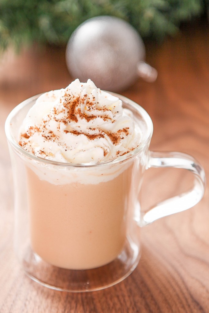a chai tea latte in a clear glass mug topped with whipped cream and cinnamon.