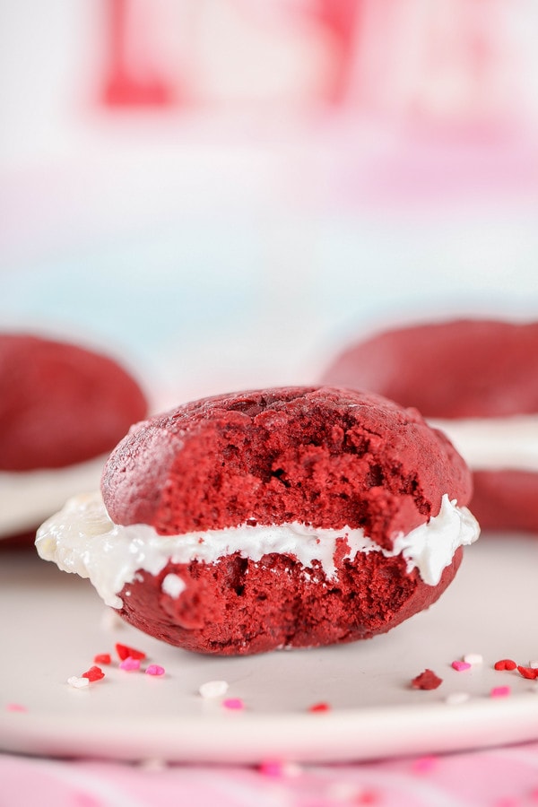 a red velvet whoopie pie with cream cheese filling with a bite taken out of it.