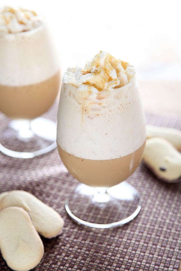 two caramel blended coffees in stemmed glasses surrounded by Milano cookies.