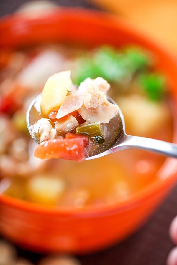 a spoon with tomato broth, clams and potatoes.