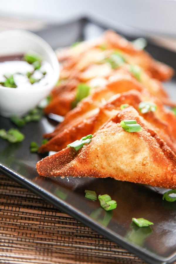 A plate of crab wontons garnished with green onions.
