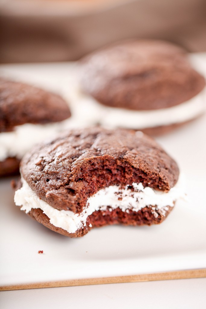 a chocolate whoopie pie with marshmallow filling with a bite taken out of it. 