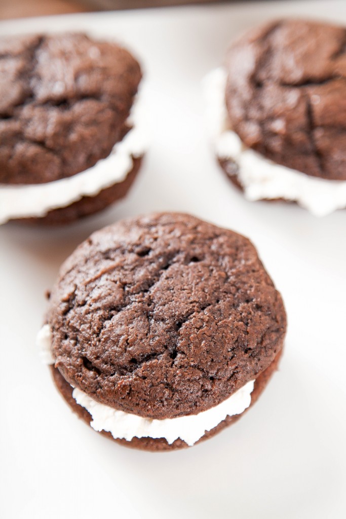 three chocolate whoopie pies but marshmallow buttercream on a white plate. 
