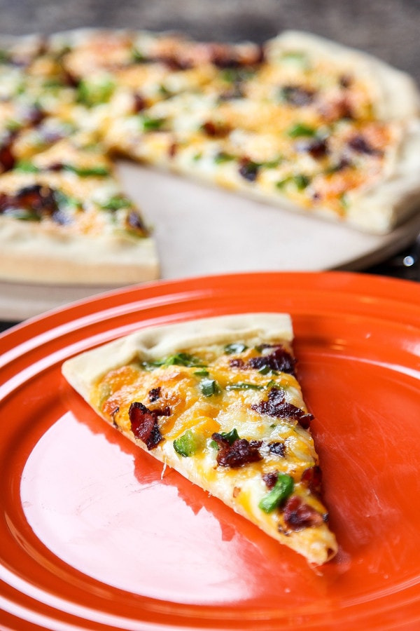 a slice of pizza with jalapenos, bacon, and cheddar cheese.