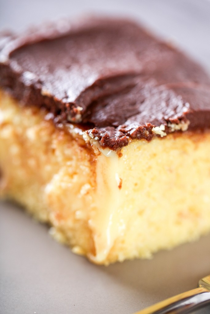 a close up image of a Boston cream poke topped with chocolate frosting. 