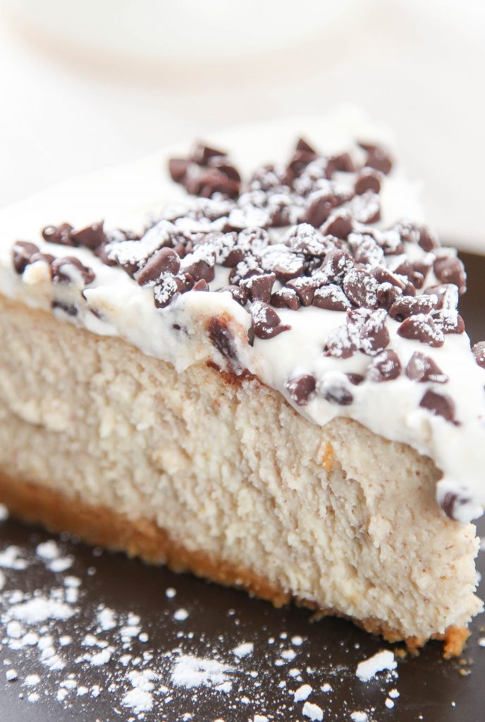 a closeup of a slice of cannoli cheesecake with chocolate chips and whipped cream.