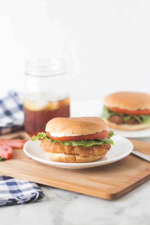 a fried pork chop sandwich with lettuce, tomato, and mayonnaise.