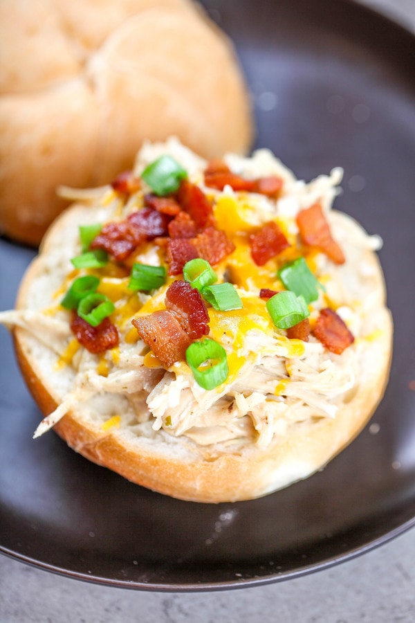 an open faced bun topped with shredded crack chicken, cheese, bacon, and green onions.