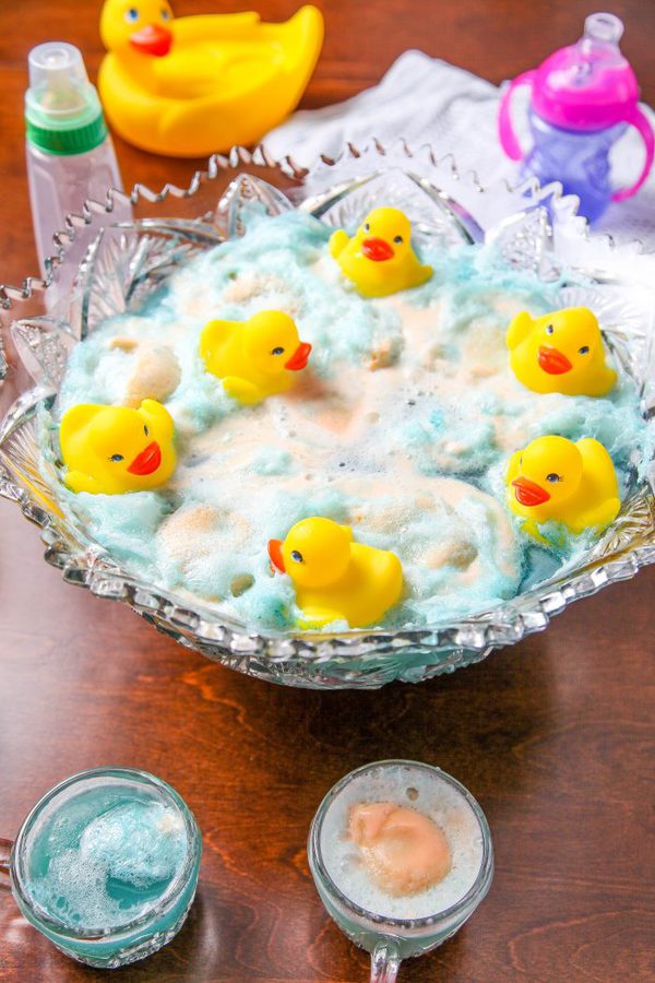 a glass punch bowl with with blue punch, sherbet, and floating rubber ducks. 