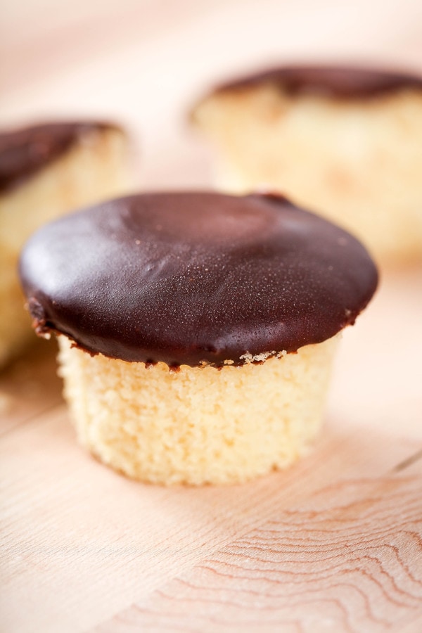 a vanilla cupcake topped with shiny chocolate ganache.