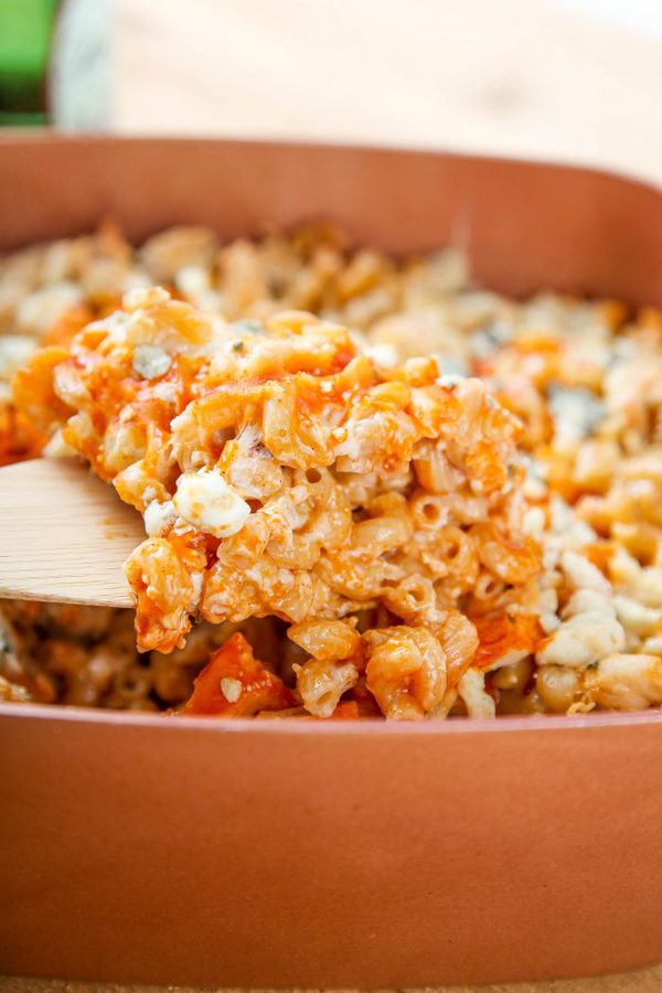 a wooden spoon lifting out a helping of buffalo chicken mac and cheese.