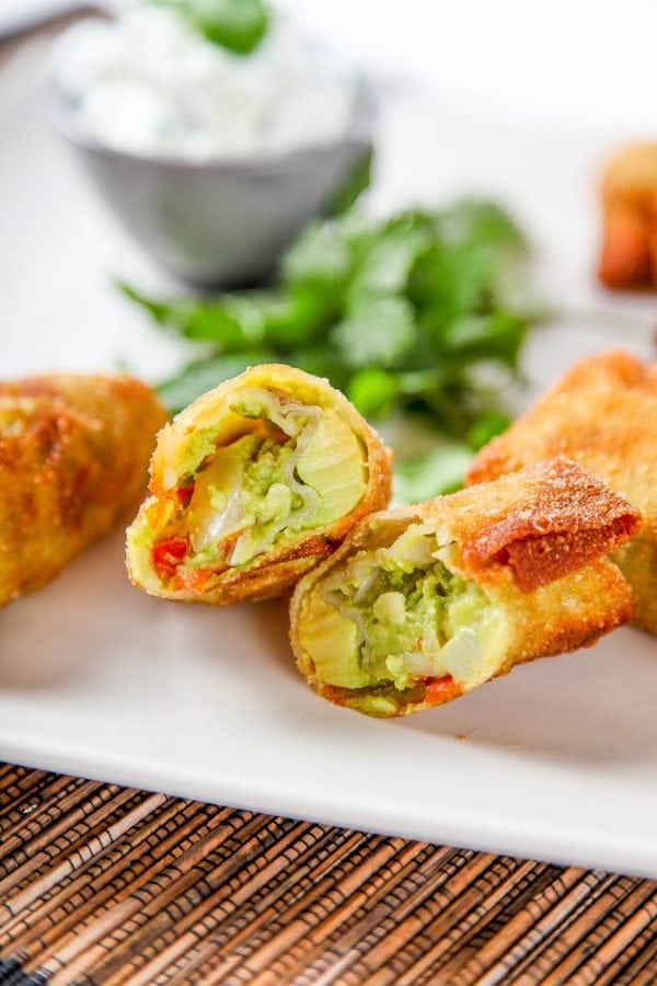 an egg roll cut in half and filled with avocado, onion, and tomatoes. 