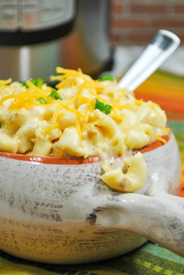 mac and cheese topped with more cheese and fresh herbs in a pottery bowl. 
