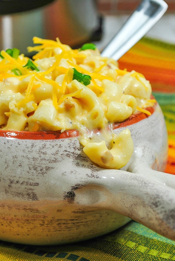 instant pot mac and cheese topped with shredded cheese and fresh herbs in a pottery bowl. 