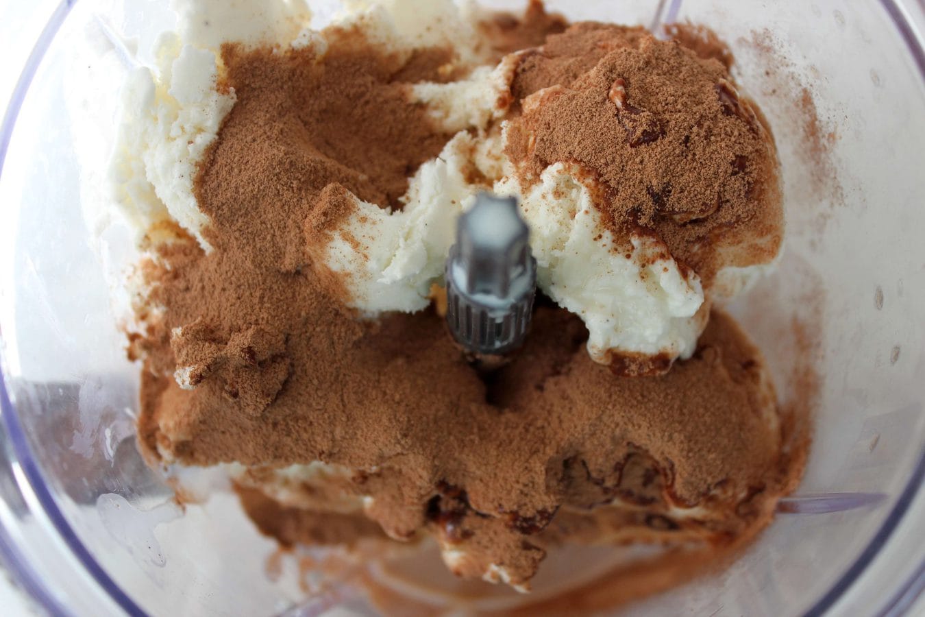 a blender with vanilla ice cream and nequik powder inside. 