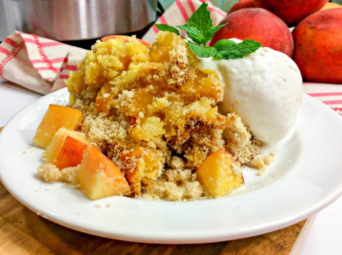 a closeup of a peach dump cake with peaches and an instant pot in the background.