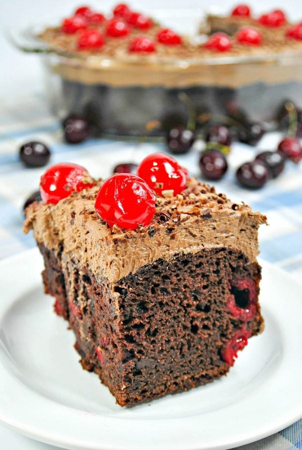 a chocolate cake with cherries topped with chocolate frosting and maraschino cherries. 
