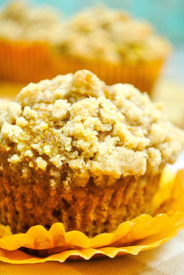 a closeup of a pumpkin streusel muffin with more muffins in the background.