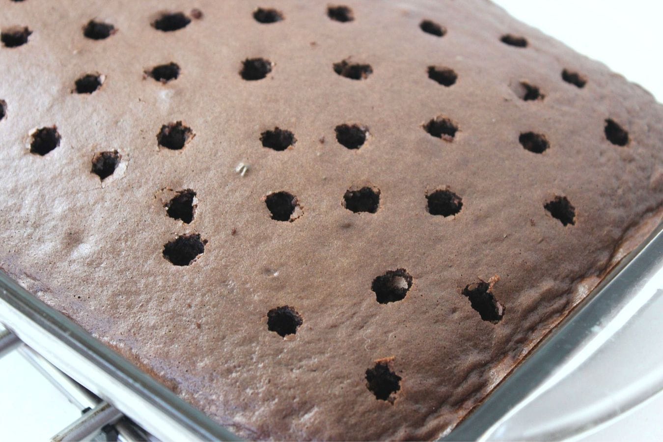 a chocolate poke cake with holes poked in it.