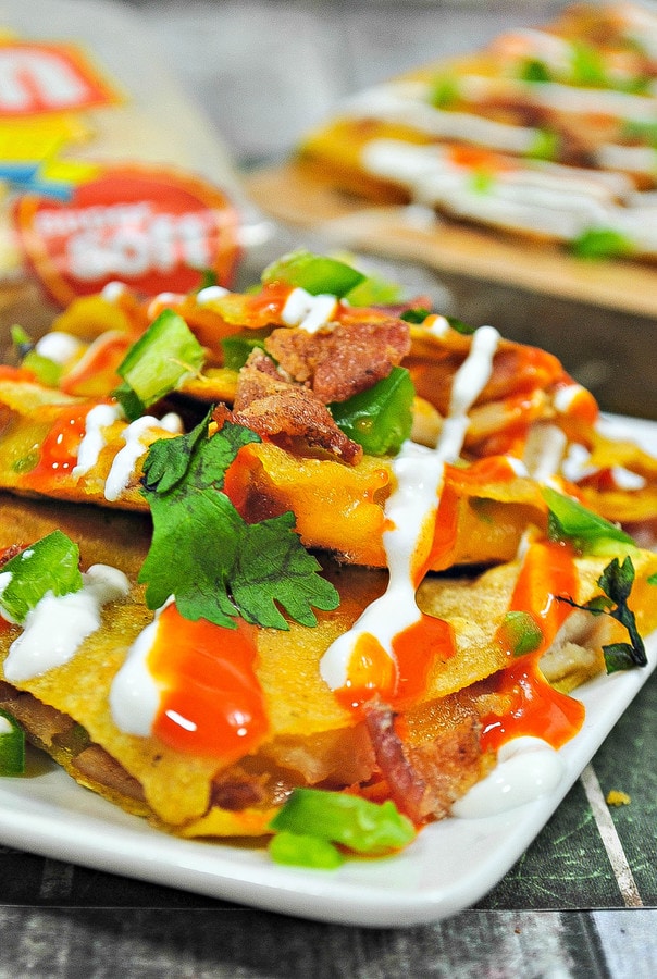 a closeup of  chicken quesadilla triangles topped with bacon, jalapenos, and buffalo sauce. 