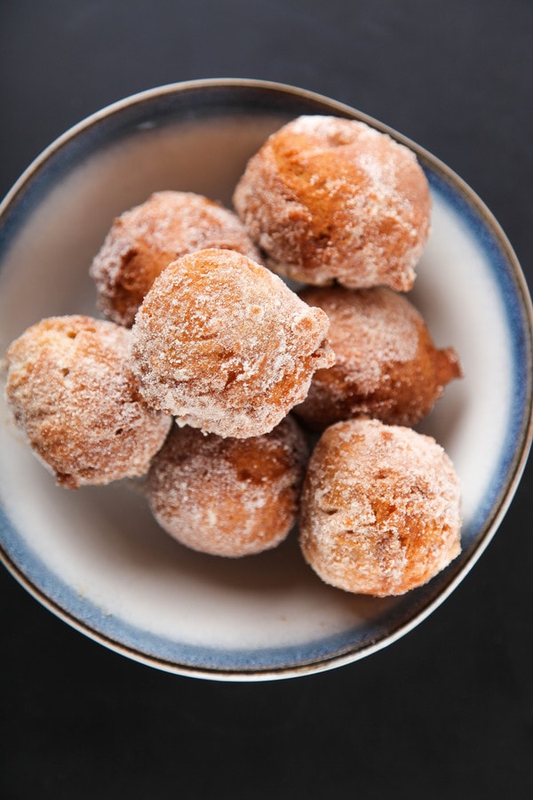 an overhead shot of cinnamon sugar donuts in a blue and white bowl. 