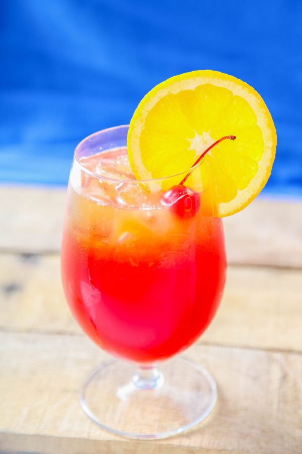 a hurricane cocktail garnished with an orange slice and a maraschino cherry. 