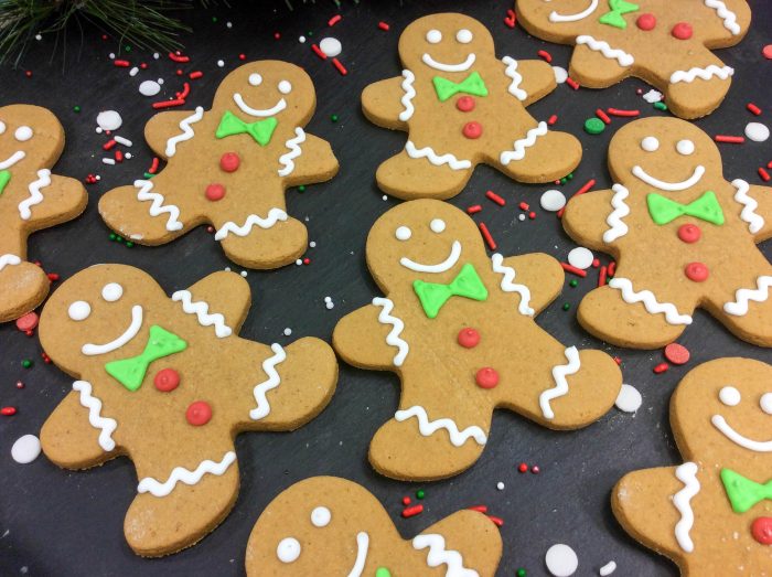 gingerbread men cookies on a black background with sprinkles scattered around.