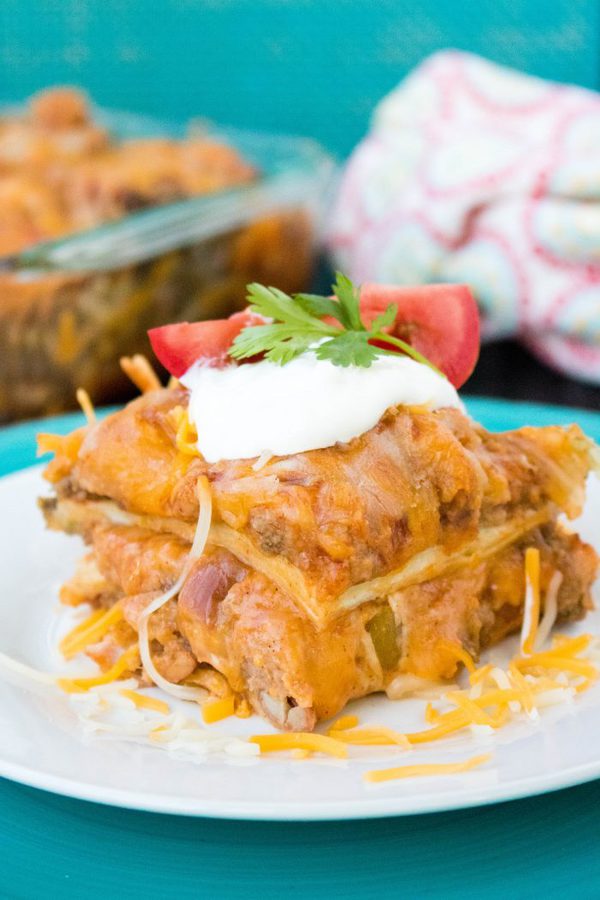 a two layer enchilada casserole with beef and cheese topped with sour cream.