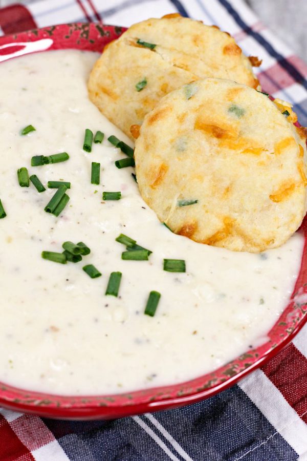 a bowl of potato soup topped with chives and homemade cheddar biscuits.