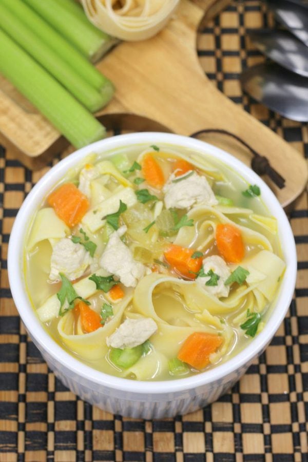 instant pot chicken noodle soup with celery and pasta in the background. 
