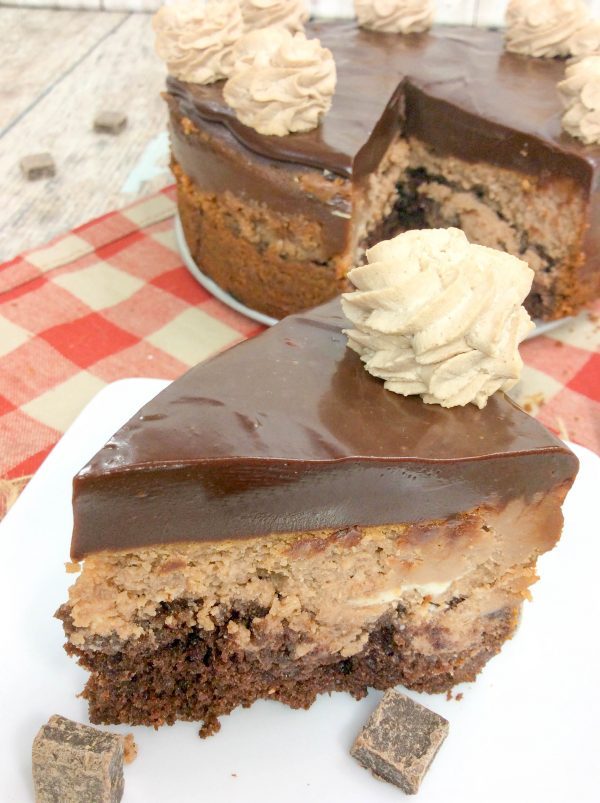 a slice of nutella cheesecake topped with chocolate ganache with chocolate whipped cream.