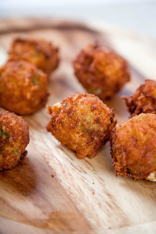 breaded pepperjack cheese bites on a wooden cutting board.