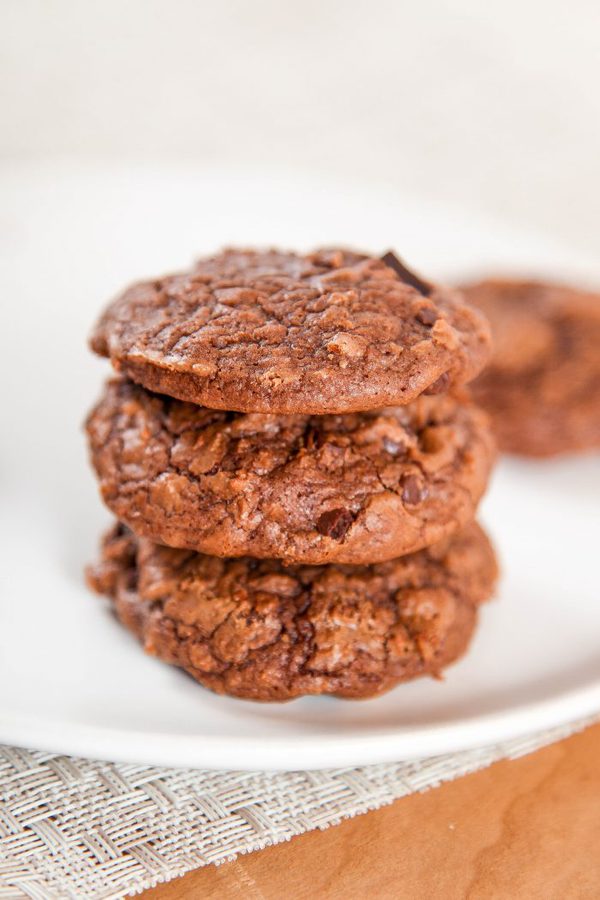 a stack of three brownies cookies with chocolate chips on a white plate. 