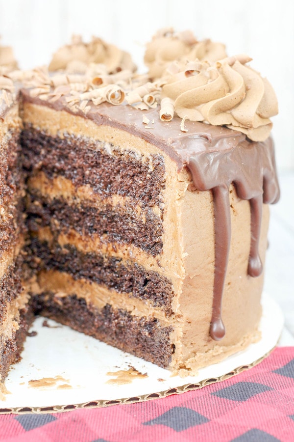 a cut open chocolate cake with chocolate buttercream rosettes and a chocolate ganache drizzle.