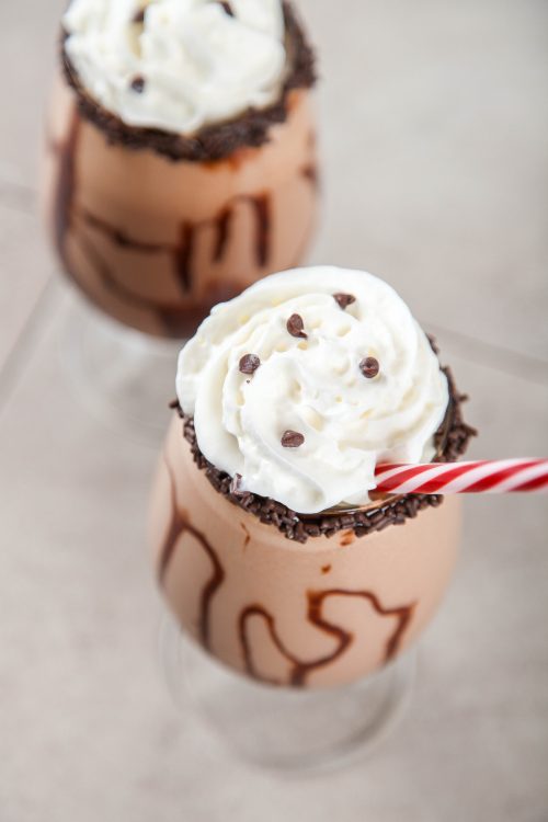 a chocolate mudslide cocktail topped with whipped cream and chocolate chips.