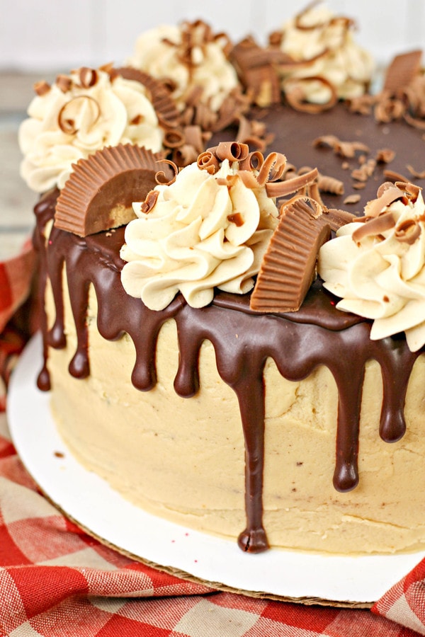a cake with peanut butter frosting, a chocolate ganache drip, and Reese's peanut butter cups.