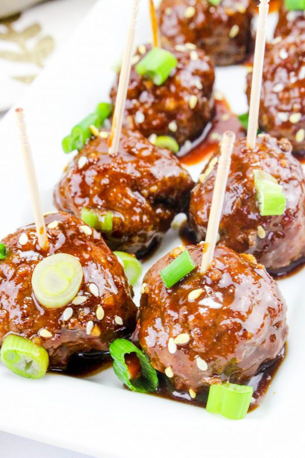 meatballs in a tangy asian sauce with green onions and toothpicks inserted in the top of each.