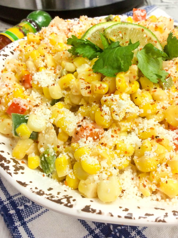 a closeup of mexican corn salad with cotija cheese, jalapenos, and limes.