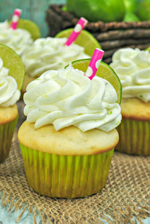 margarita cupcakes topped with lime buttercream, lime slices, and small pink straws.