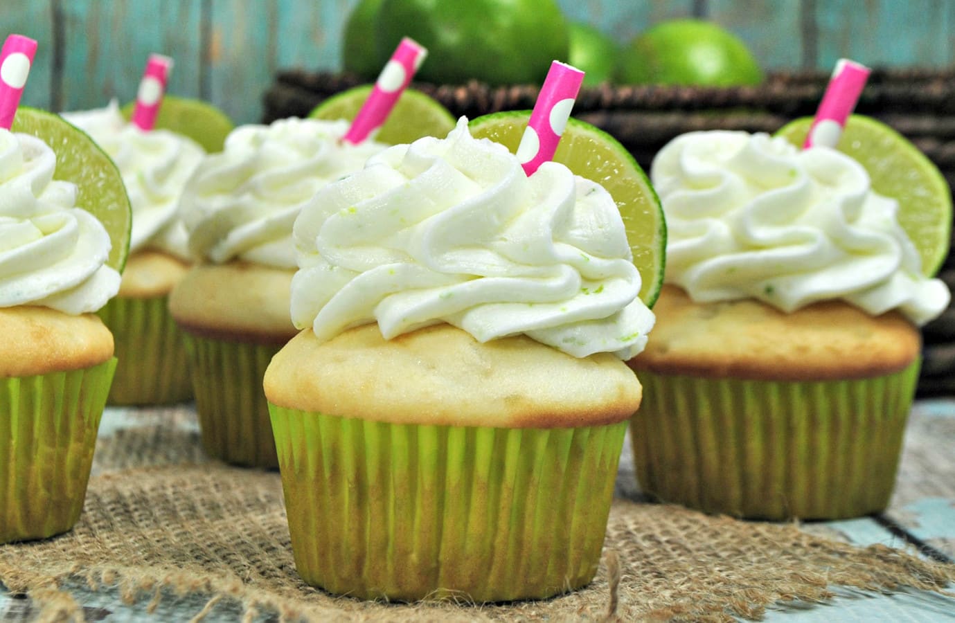 lime cupcakes with tequila buttercream and lime slices on a burlap placemat. 