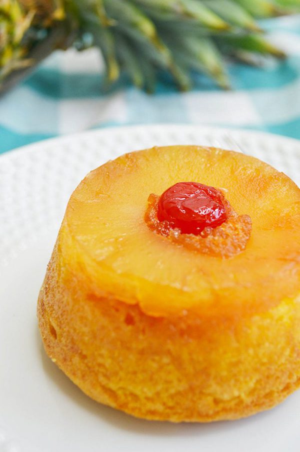 a closeup of a mini pineapple upside down cake with a ring of pineapple and a cherry on top.